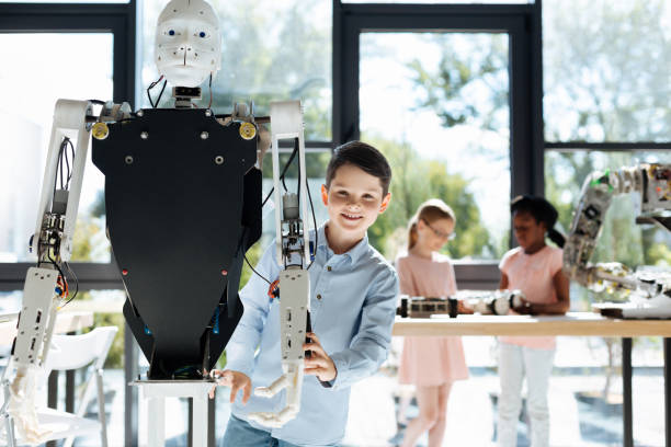 istock Dark-haired boy standing near a human robot 820858262