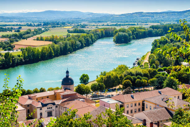 High angle view landscape of Trevoux town scenic in France along Saone river during a sunny summer day High angle view of trees, fileds, house roof, Saone river and Beaujolais hills in background of Trevoux beautiful town landscape in summer season with a bright sunlight. This pretty medieval town is located in Ain, Auvergne-Rhone-Alpes region in France near Lyon city along Saone river. ain france photos stock pictures, royalty-free photos & images