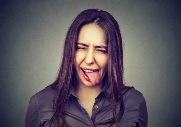 Portrait of beautiful woman in casual clothes showing her tongue Portrait of beautiful woman in casual clothes showing her tongue sour face stock pictures, royalty-free photos & images