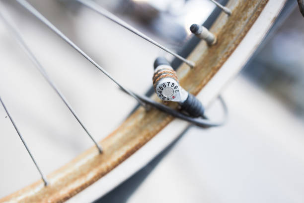 Bicycle hub with old, rusty nuts and spokes in a city setting, highlighting signs of use and aging.