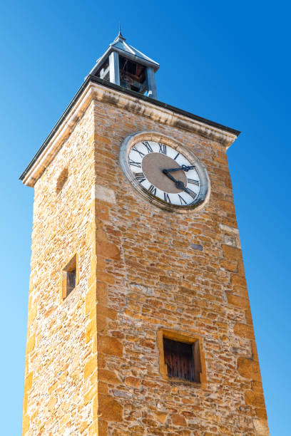 istock Close-up low angle view of old medieval clock tower architecture with pretty modern replaced clock on blue sky 820863238