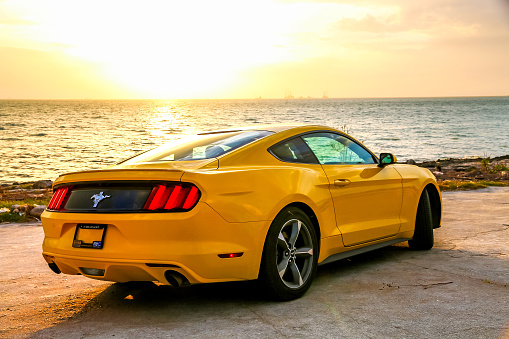 Campeche, Mexico - May 20, 2017: Yellow muscle car Ford Mustang at the shore of the Gulf of Mexico.