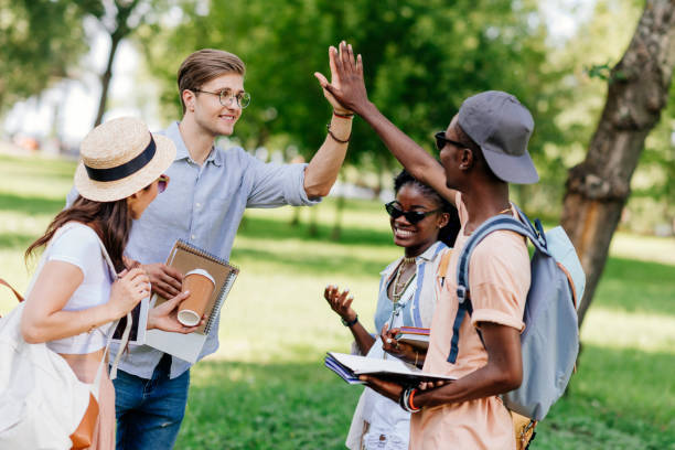 istock cheerful young multiethnic students giving high five while standing together in park 820865154