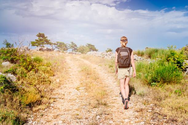 Young woman with backpack at mountain trail. Sveti Nikola mount, Hvar Island, Croatia