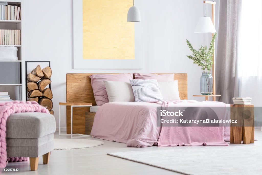 Big wooden bed Big wooden bed with pink bedding in cozy white bedroom Home Improvement Stock Photo