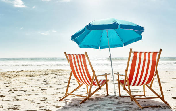 Get some summer in your life Still life shot of two deck chairs under an umbrella on the beach deck chair stock pictures, royalty-free photos & images
