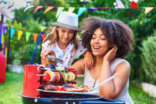 istock Smiling mother and daughter making barbecue at backyard 820874558