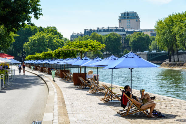 Alignment of parasols and deck chairs in the sun on the wharf of the river Seine. Paris, France - July 18, 2017: Every summer since 2002, "Paris Plage" event creates the environment of a seaside town, with artificial beaches, refreshment bars, terraces, parasols and deck chairs. seine river stock pictures, royalty-free photos & images