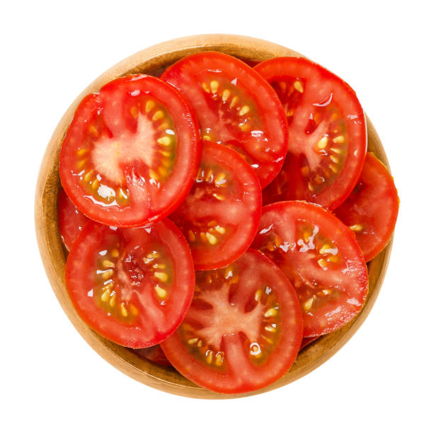 istock Tomato slices in wooden bowl over white 820889478