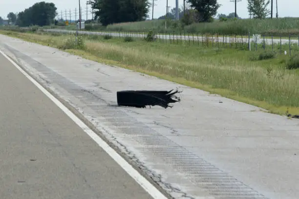 A piece of a shredded tire lies on the shoulder of Interstate 55.  Beyond the fence is the "mother road", historic route 66