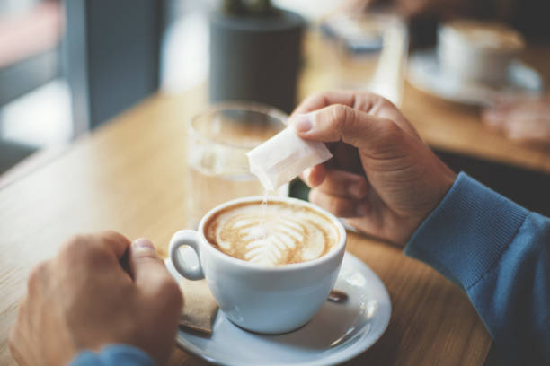 giovane che mette lo zucchero nel suo caffè - pouring coffee human hand cup foto e immagini stock