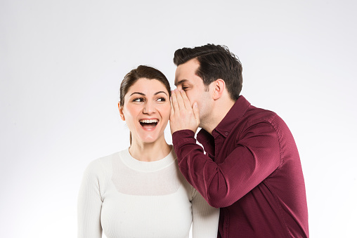 A man whispering to his wife on white background