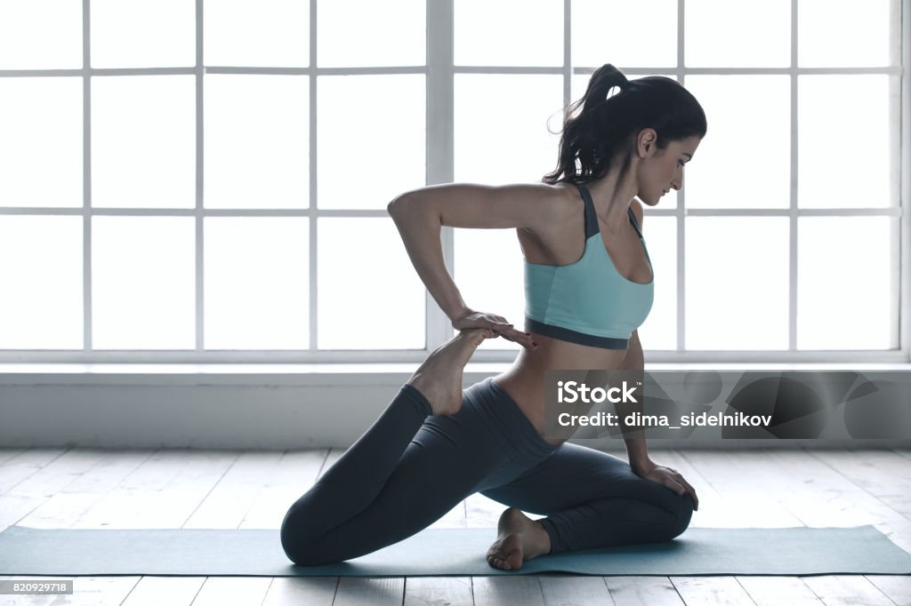 Young Woman Doing Yoga Pose Exercise Healthy Lifestyle Young woman doing yoga asana exercise indoors near window Adult Stock Photo