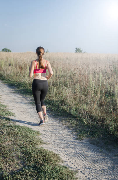 istock Beautiful woman running on field road during sunset 820933302