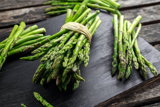 fresh raw green asparagus on wooden chopping board - raw food green freshness imagens e fotografias de stock