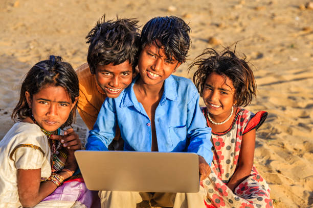 istock Group of happy Gypsy Indian children using laptop, India 820953348