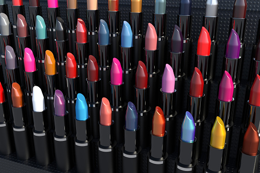High resolution digital image of dozens of lipsticks displayed in rows. Lipsticks are various colors, and each is in a non-descript, generic plastic housing, that mixes both glossy and matte surfaces.