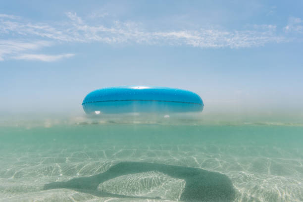 Blue rubber ring floating on the sea, Pedn Vounder Beach, near Porthcurno, South Cornwall on a bright sunny June day.