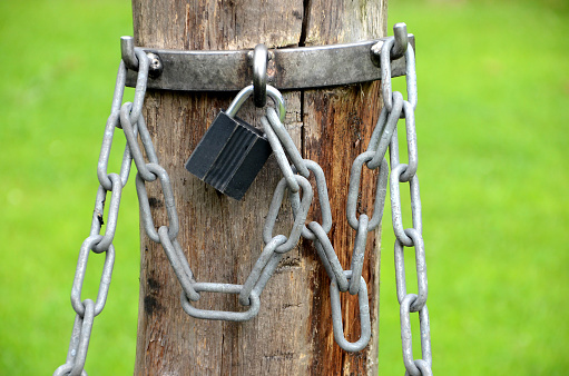 Padlock with chains on a wooden pole.
