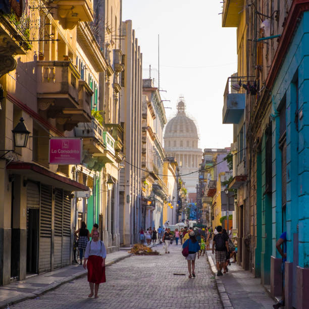 Group of several people walking and carrying out everyday life in the street of the old Havana. The capitolio in the background