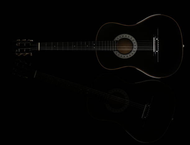 istock Black acoustic guitar isolated on black reflective surface, standing vertical 820991464