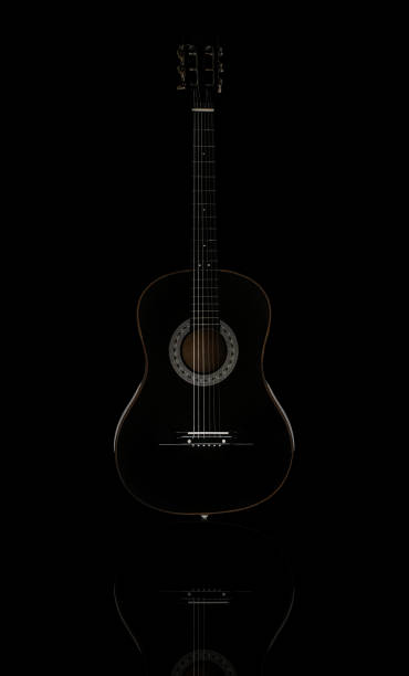 negro guitarra acústica aislada en superficie reflectante negro, vertical de pie - musical instrument string music dark old fashioned fotografías e imágenes de stock