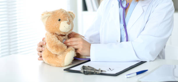 istock Female doctor examining a Teddy bear  patient by stethoscope. 820994346