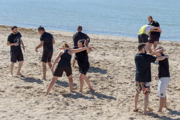 Two girls train are engaged in wrestling on the seashore Large group of young people, girls and boys, are engaged in wrestling on the seashore. Sitges, Catalonia, Spain - May 20, 2017 wrestlers uniform stock pictures, royalty-free photos & images