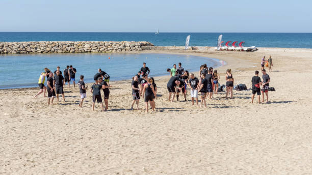 Large group of young people, girls and boys, are engaged in wrestling on the seashore. General plan Large group of young people, girls and boys, are engaged in wrestling on the seashore. General plan. Outdoor sporting activity. Summer meer landscape. Sitges, Catalonia, Spain - May 20, 2017 wrestlers uniform stock pictures, royalty-free photos & images
