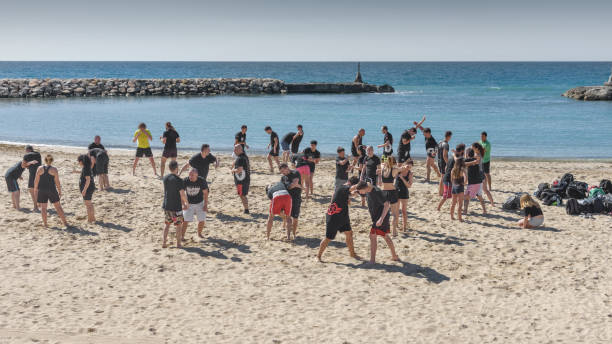Large group of young girls and boys, are engaged in wrestling on the seashore. General plan Large group of young people, girls and boys, are engaged in wrestling on the seashore. Outdoor sporting activity. General plan. Sitges, Catalonia, Spain - May 20, 2017 wrestlers uniform stock pictures, royalty-free photos & images