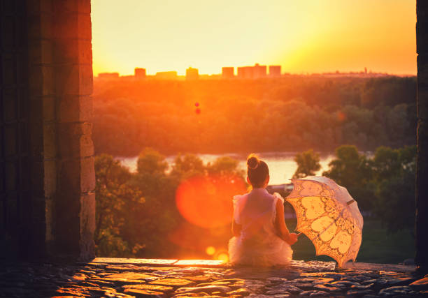 Beautiful little princess with sunshade enjoying at sunset