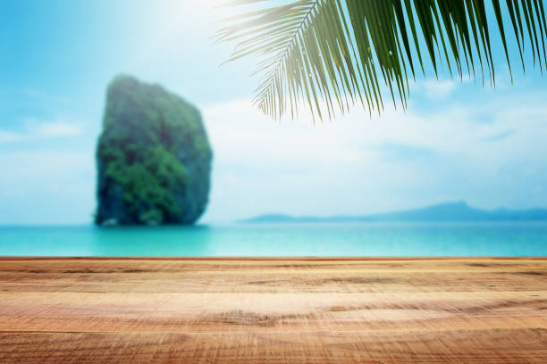istock Beautiful blurred beach background with palm tree and wooden table. 821024906