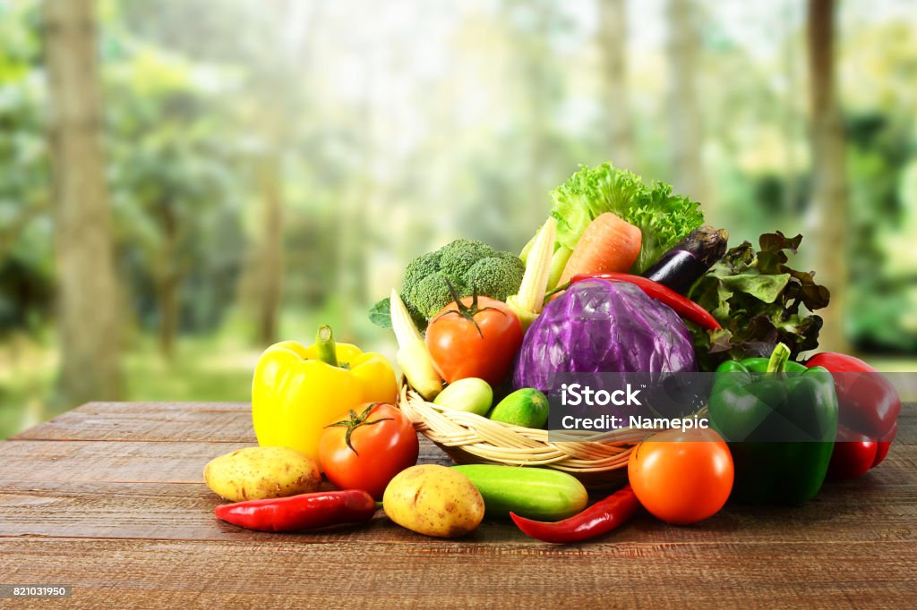 Verduras frescas en la mesa de madera y fondo de naturaleza borrosa. - Foto de stock de Vegetal libre de derechos