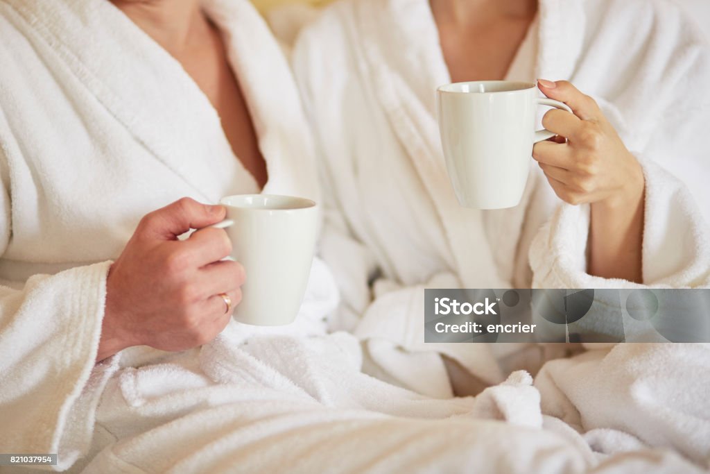 Coppia in accappatoi bianchi a letto, bevendo caffè - Foto stock royalty-free di Albergo