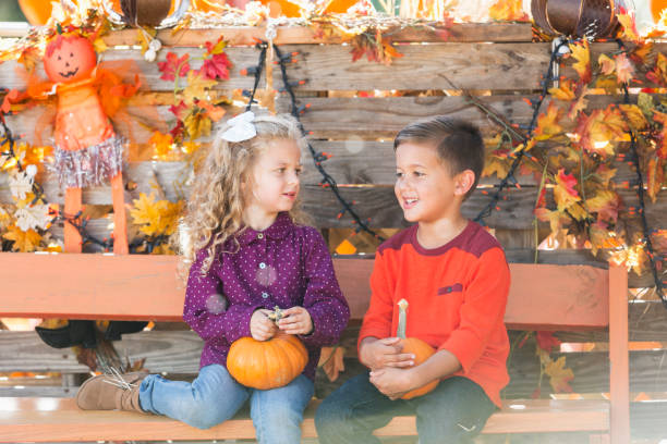 garçon et fille, assis sur un banc à l’automne - child autumn scarecrow decoration photos et images de collection