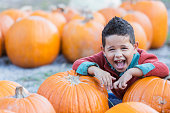 Hispanic boy playing in pumpkin patch