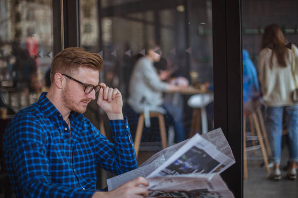 istock Handsome man reading newspaper in cafe 821052112
