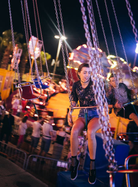 istock Cool young friends having fun riding amusement park swing carousel 821057332