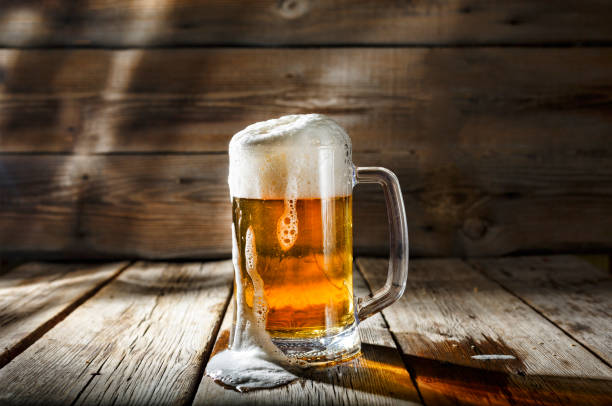 Mug of light beer with foam on a wooden table in a pub stock photo