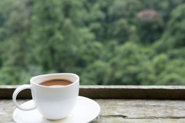 istock hot coffee in white cup on wood table with green nature background 821087856