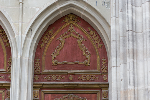 entrance door and ornaments of romantic catholic church in south germany historical city with red orange colors and silverplating ironwork handicraft