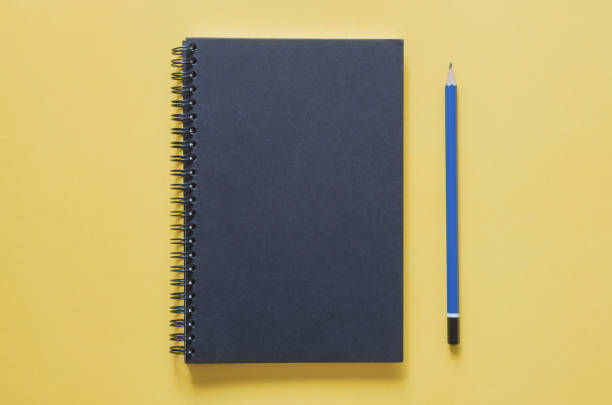 istock Office workplace minimal concept. Black notebook and pencil on yellow background. 821150516