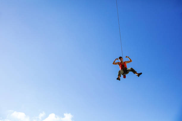 istock Rock climber swinging on rope and flexing muscles 821154562