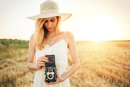 Young woman photographer capturing moment with retro styled camera.
