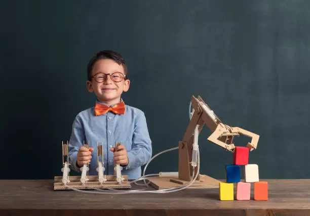 Photo of Cute child invented robot arm with cardboard.