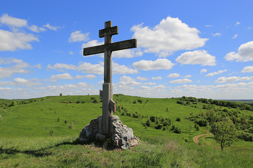 Cross on green hill in sunny day