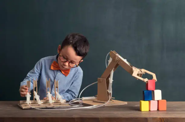Photo of Cute child invented robot arm with cardboard.