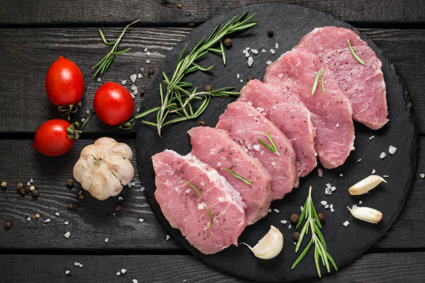Raw boneless pork chops, vegetables, herbs and spices stock photo