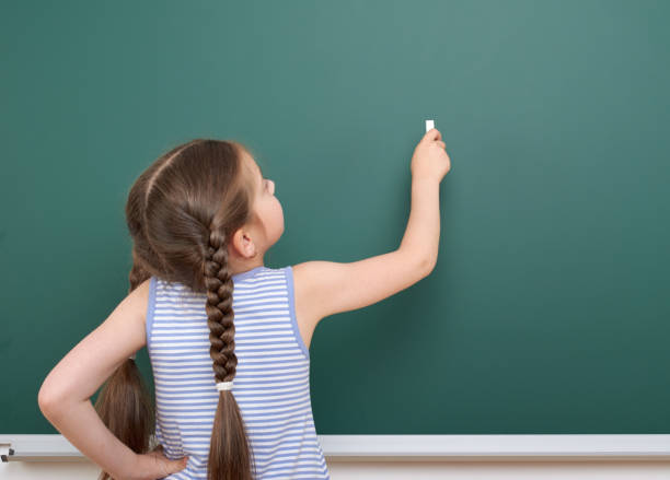 istock Schoolgirl writing chalk on a blackboard, empty space, education concept 821183562