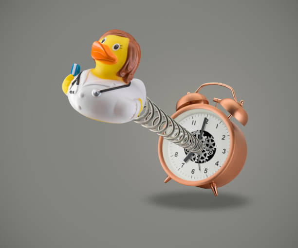 Rubber duck Doctor coming out of alarm clock stock photo